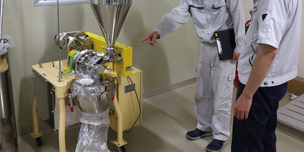 Pointing at the milling machine with the updated hopper component installed